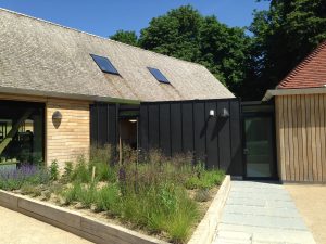 photo shows a view of completed cedar shake roof, pitched tiled roof and standing seam zinc cladding completed by Kingsley Roofing in Chichester