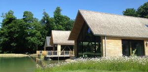 View of visitors centre next to a picturesque lake with roofs covered in handmade cedar shakes installed by Kingsley Roofing